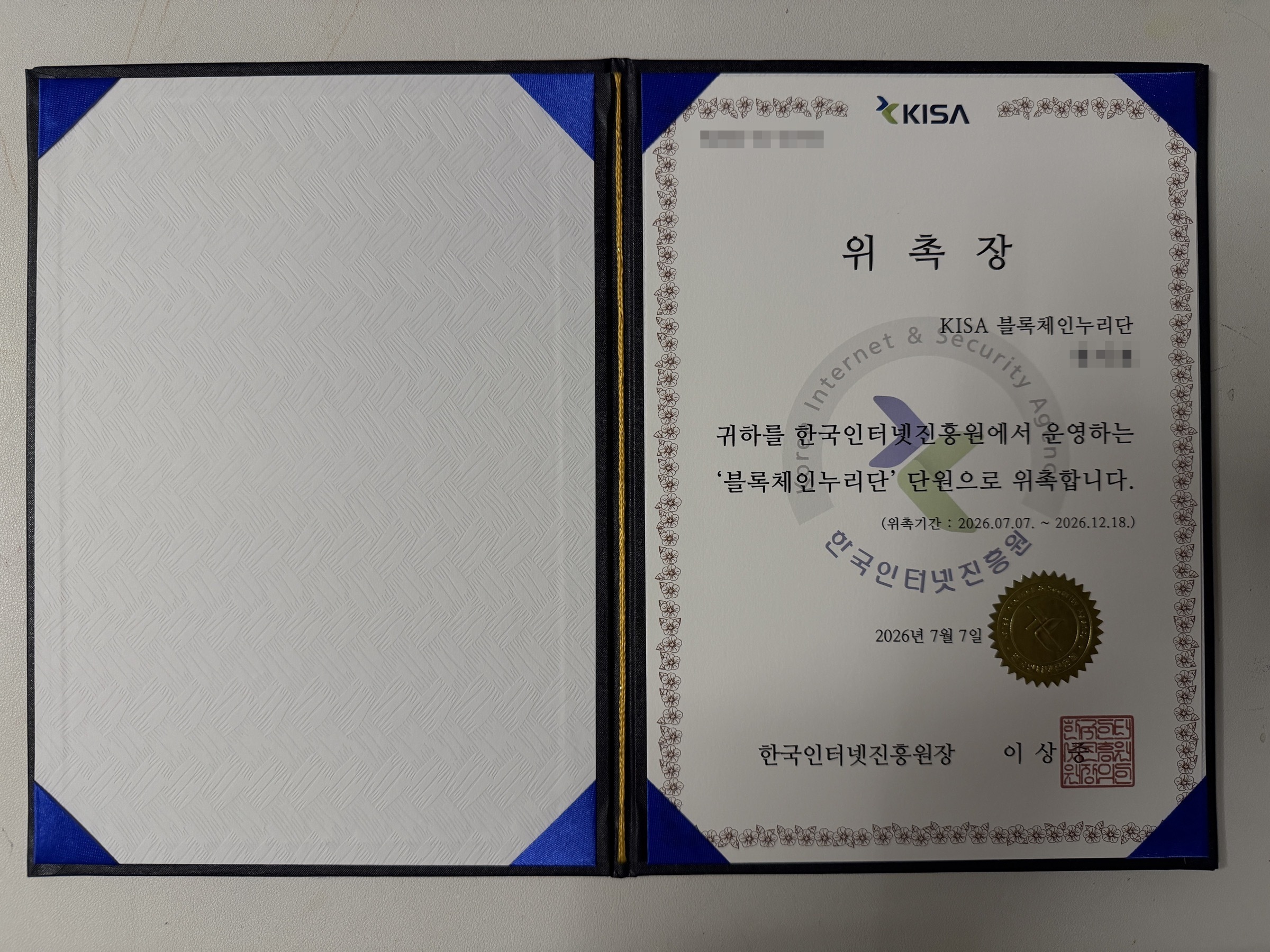 한국인터넷진흥원장 명의의 KISA 블록체인누리단 위촉장 - 위촉기간 2026년 7월 7일부터 12월 18일까지가 명시되어 있고 금박 직인이 찍혀 있습니다. 개인정보는 흐림 처리했습니다