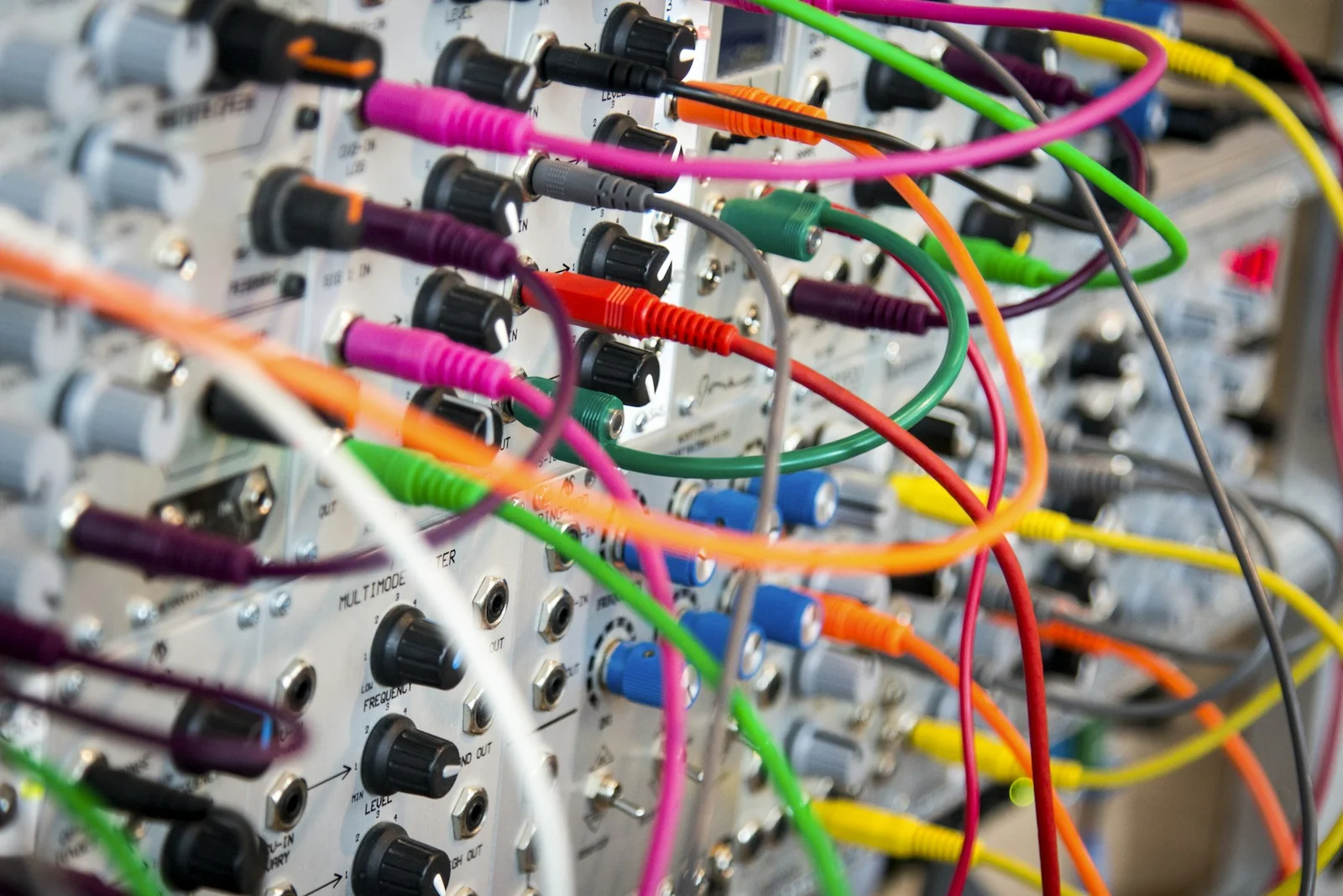 Dozens of colorful patch cables tangled together in the jacks of a modular synthesizer - add one cable at a time and eventually nobody knows the whole picture anymore, and web page complexity grows the same way